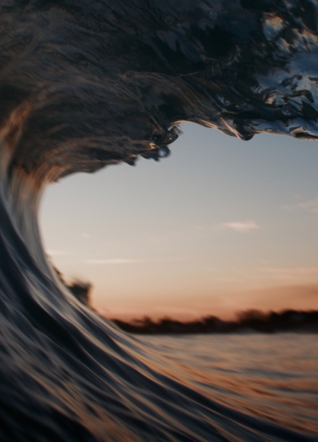 A wave curling over itself at dusk, seen from inside the break